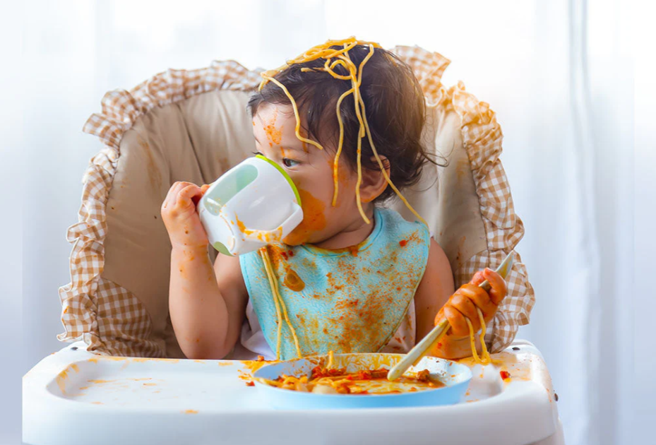 Baby eating solid foods and making a happy mess during weaning